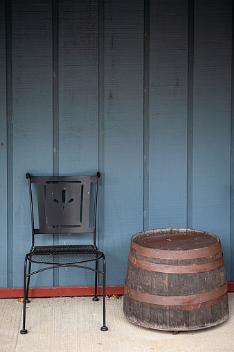 Rustic metal chair and wooden barrel against blue wall