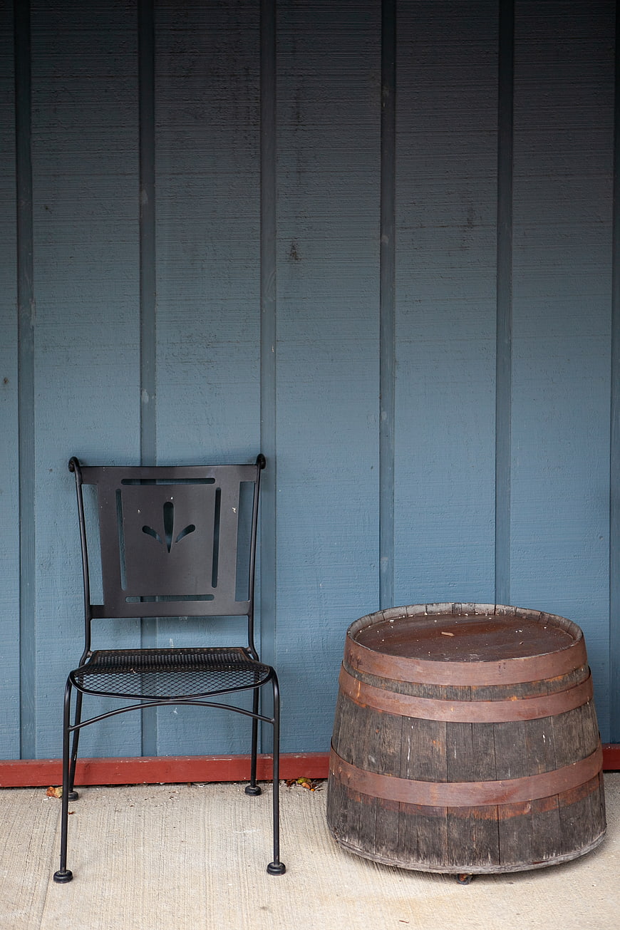 Rustic metal chair and wooden barrel against blue wall