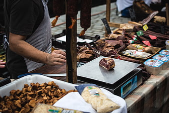 Meat vendor weighing cured ham at outdoor market