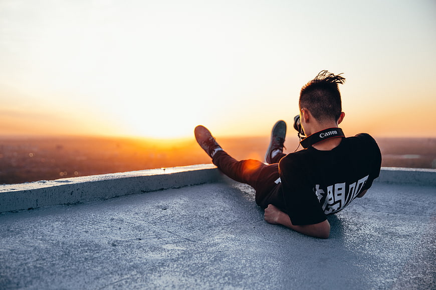 Photographer with Canon Camera Relaxing on Rooftop at Sunset