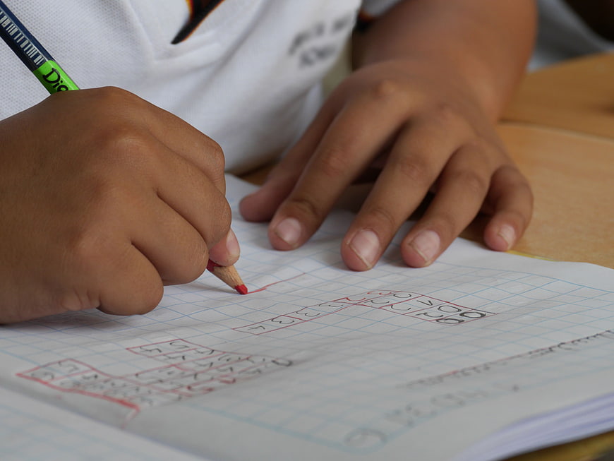 Child Writing Numbers in Graph Paper Notebook