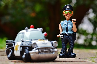 Toy policewoman figurine with police car outdoors