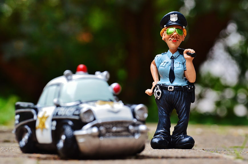 Toy policewoman figurine with police car outdoors