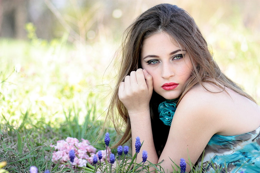 Beautiful young woman lying in spring flowers