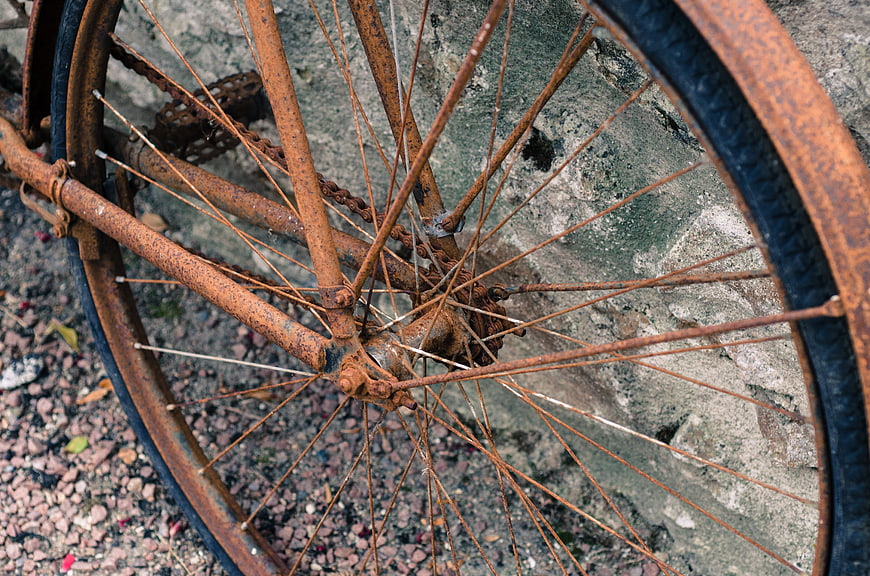 Close-up of rusty vintage bicycle wheel on gravel
