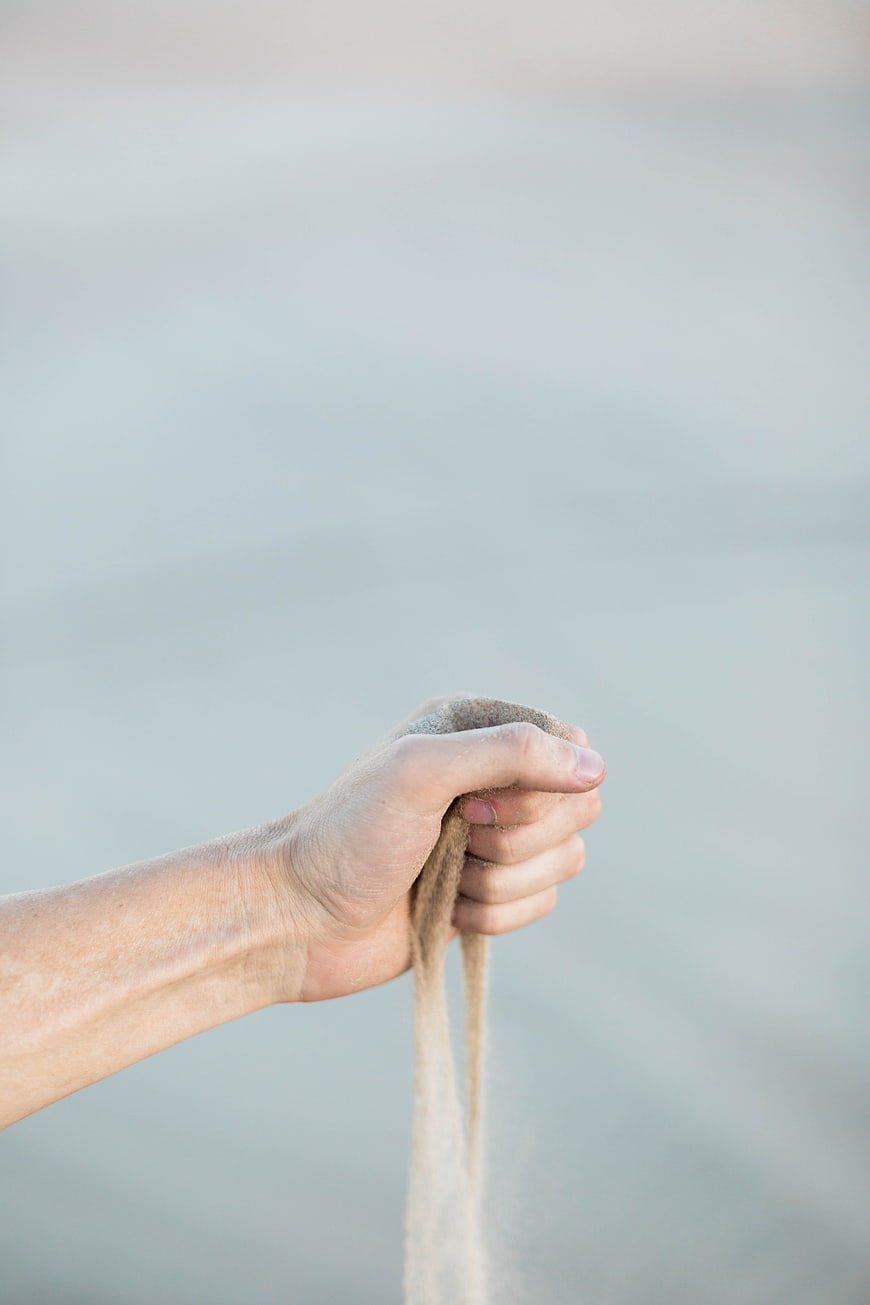 Hand Holding Sand with Ocean Background