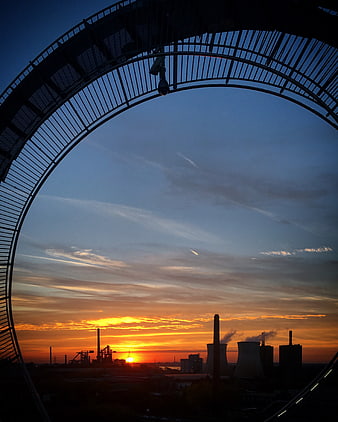 Industrial Silhouette at Sunset Through Circular Arch