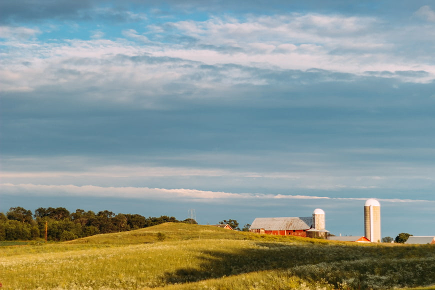 Red Barn and Silos on Rolling Green Hill Landscape