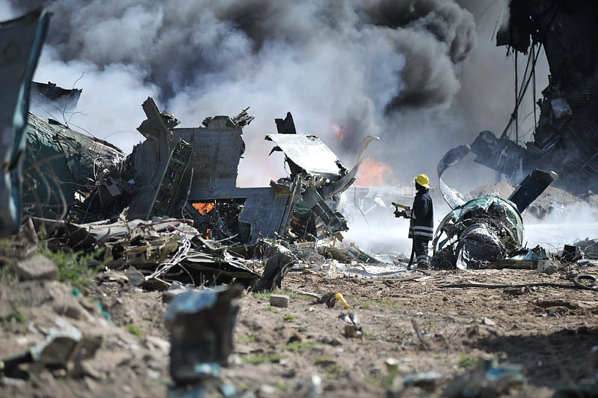 Firefighter Spraying Water on Burning Aircraft Wreckage