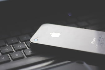 Silver iPhone on Black Laptop Keyboard Close-Up