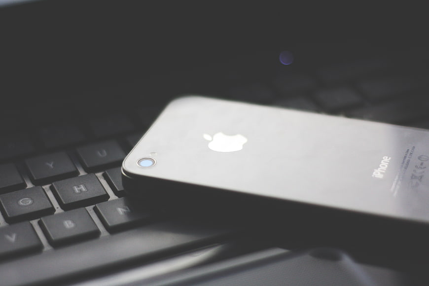 Silver iPhone on Black Laptop Keyboard Close-Up