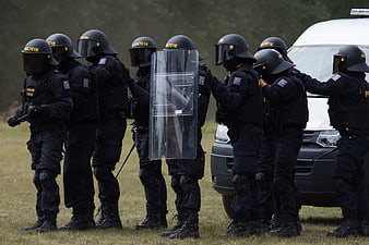 Row of riot police officers in black tactical gear and helmets
