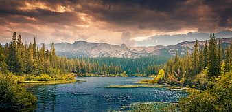 Dramatic sunset over mountain lake with pine forest