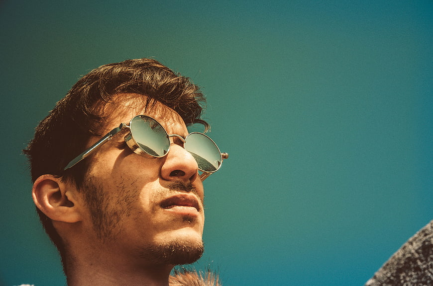 Man with Sunglasses Looking Up at Blue Sky