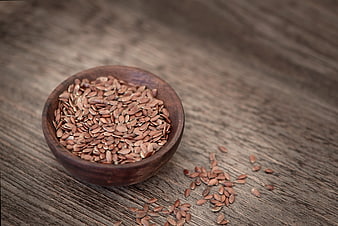 Flax seeds in wooden bowl on rustic table