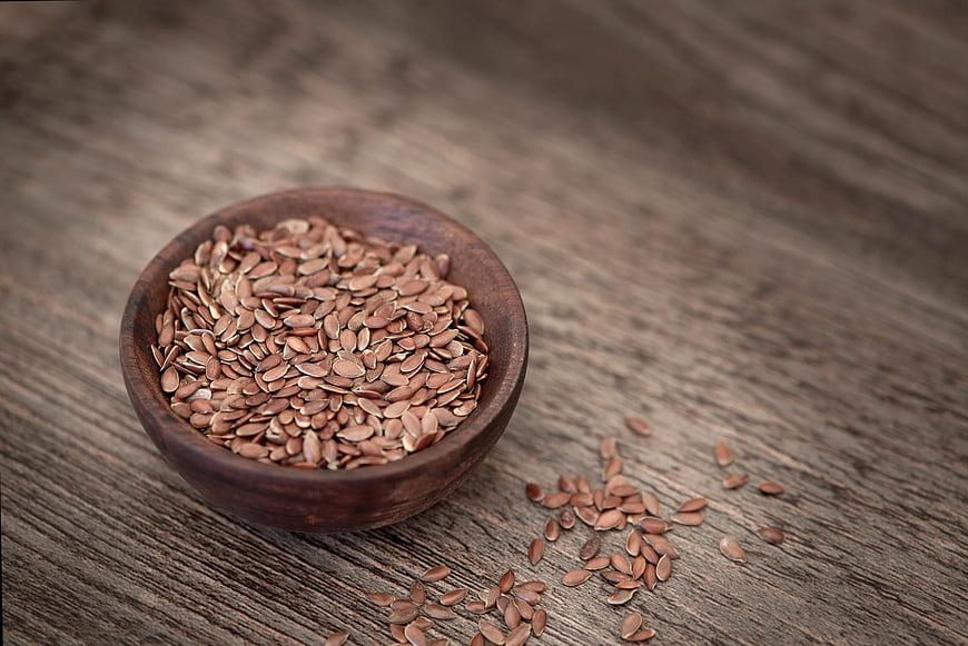 Flax seeds in wooden bowl on rustic table