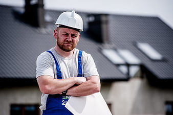 Frustrated construction worker holding blueprints on roof
