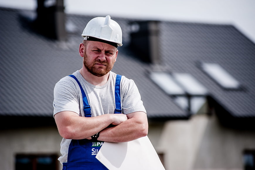Frustrated construction worker holding blueprints on roof