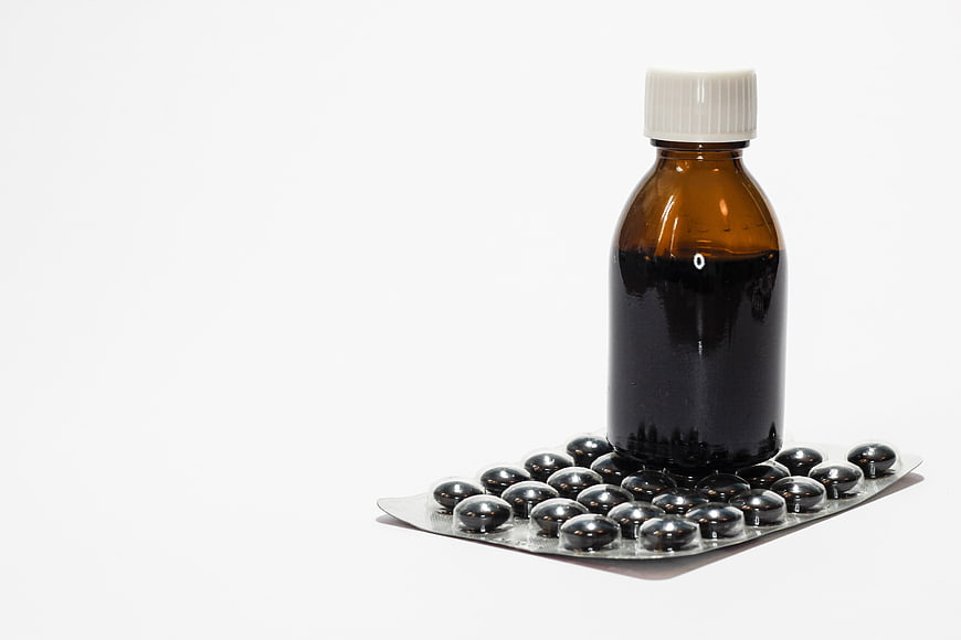 Brown medicine bottle and blister pack of pills on white background