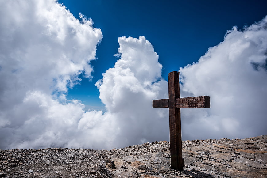 Wooden Cross on Rocky Mountain Summit with Dramatic Clouds