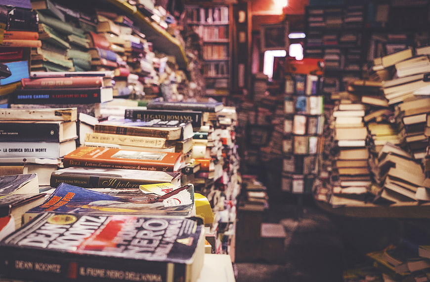 Stacks of books in a cozy, cluttered vintage bookstore aisle