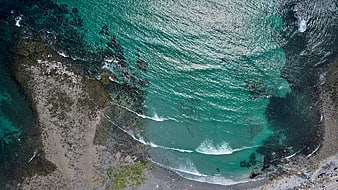 Aerial View of Turquoise Ocean Waves Crashing on Rocky Shore