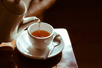 Pouring Hot Tea into White Cup on Wooden Table