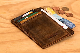 Brown leather wallet with cards and cash on wooden table