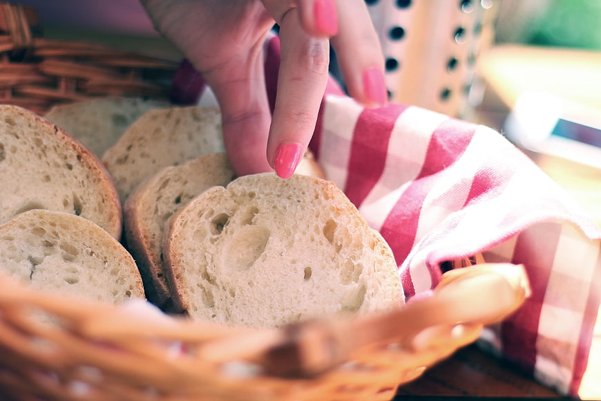 Hand Reaching for Fresh Bread Slices in Basket