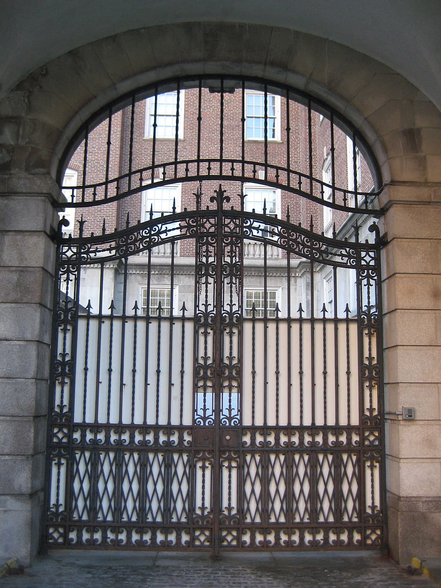 Ornate black iron gate under stone archway entrance