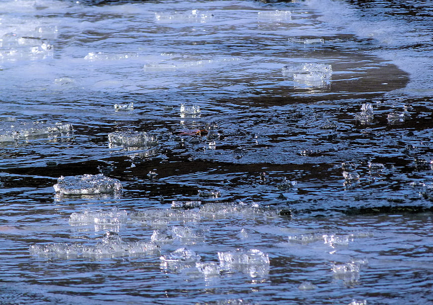 Chunks of ice floating in a flowing river stream