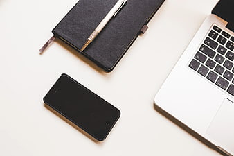 Minimalist workspace with laptop, smartphone, and notebook