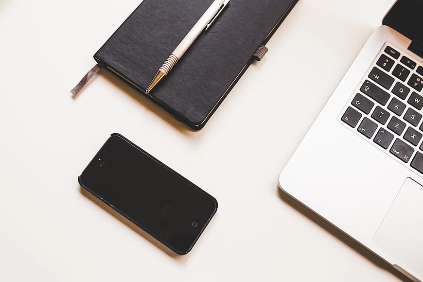 Minimalist workspace with laptop, smartphone, and notebook