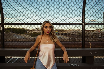 Stylish Blonde Woman Leaning on Urban Bridge Fence