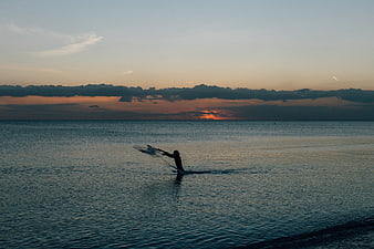 Silhouette of Fisherman Casting Net at Sunset Ocean
