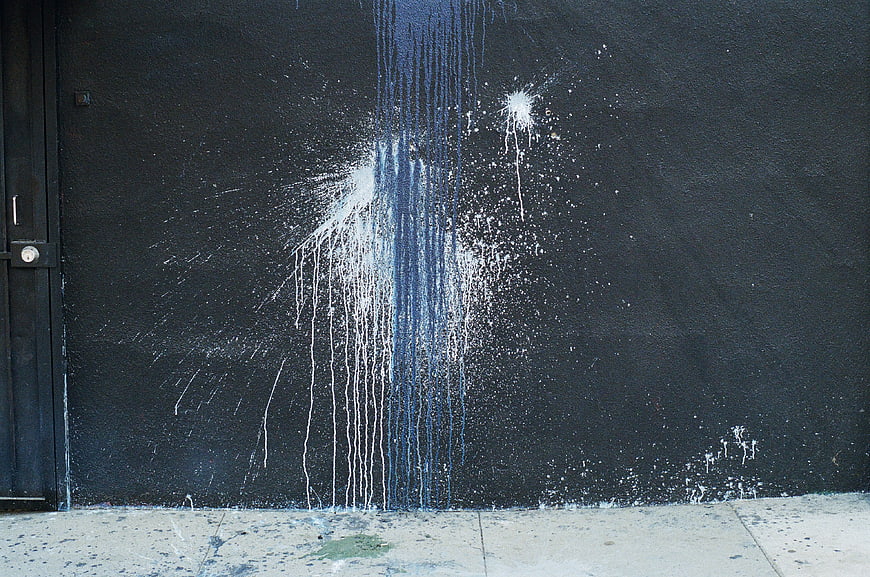 Abstract blue and white paint splatter on dark wall