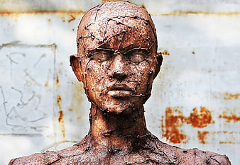 Rusty metal sculpture of a human head with wire details
