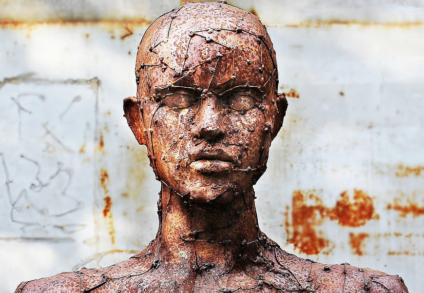 Rusty metal sculpture of a human head with wire details