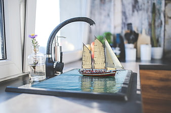 Creative photomontage of a sailboat on a kitchen sink water surface