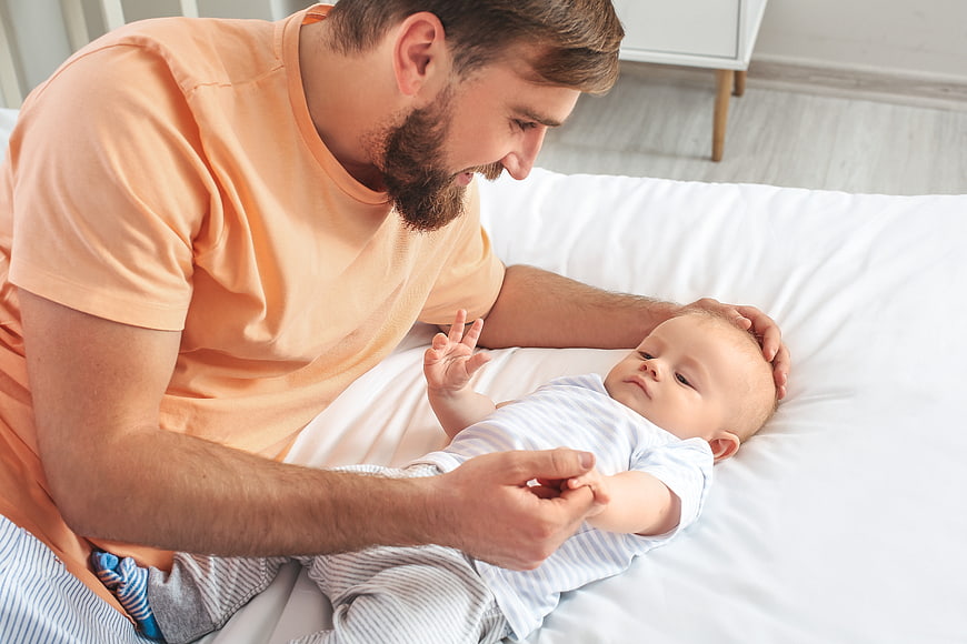 Father Playing with Newborn Baby on Bed