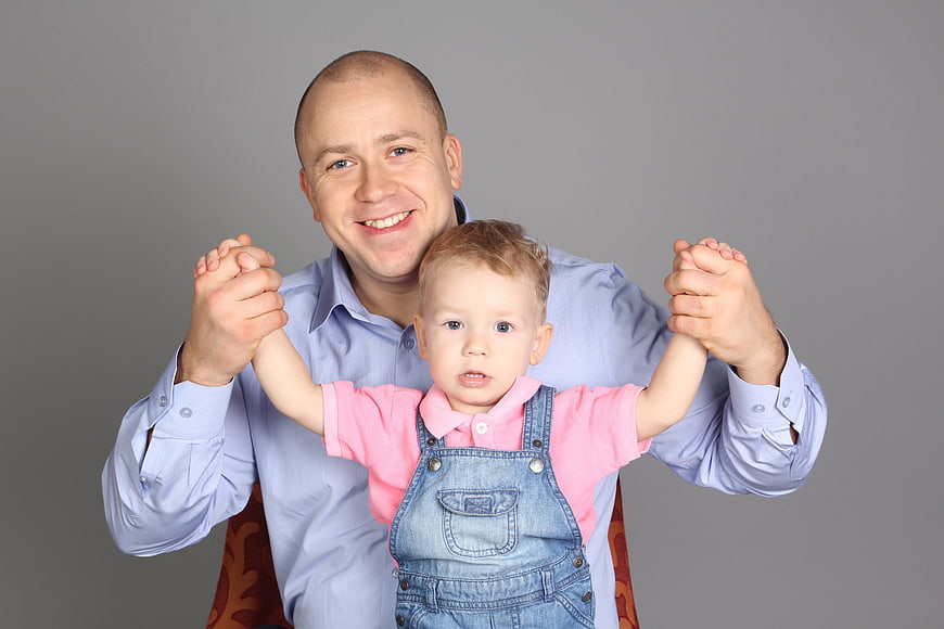 Smiling Father Holding Toddler Son In Studio