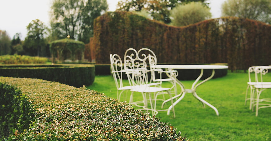 White wrought iron table and chairs in manicured garden