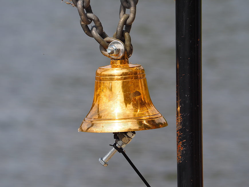 Close-up of a shiny brass bell hanging on a chain