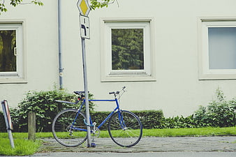 Blue Bicycle Parked on Sidewalk Near White Building