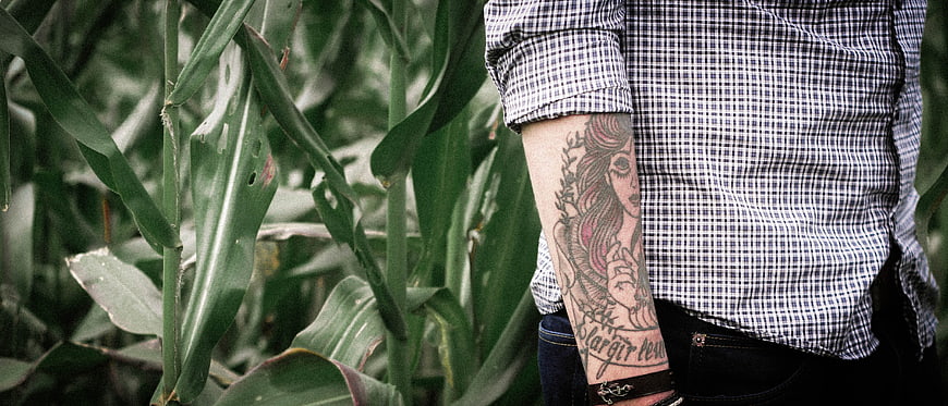 Man with Sleeve Tattoo Standing in Cornfield