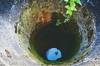Looking Down Into An Old Mossy Stone Well With Water Reflection