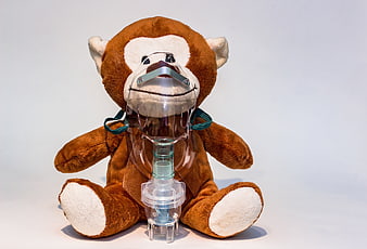 Teddy Bear Wearing Medical Nebulizer Mask on White Background