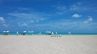 Wide shot of white sand beach with turquoise water and blue sky