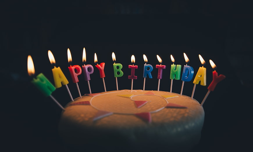 Birthday Cake with Lit Letter Candles on Dark Background