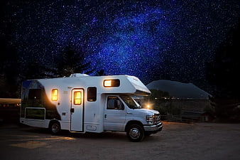 White RV parked under starry night sky with Milky Way